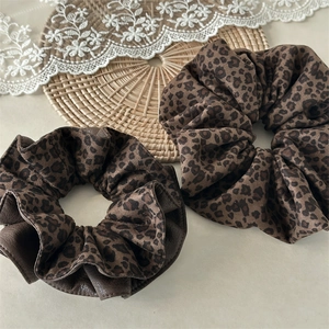 Close-up of leopard print velvet scrunchies with leather trim and fabric textures