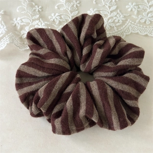 Detail of soft striped knit hair scrunchie with warm brown and beige texture