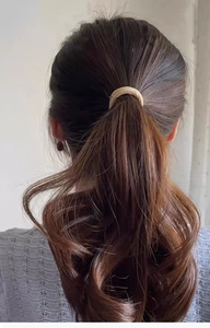 Dettaglio di un elegante elastico per capelli intrecciato dorato su coda di cavallo
