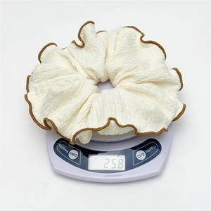 Chouchou blanc surdimensionné avec bords passepoilés marron et texture plissée sur balance