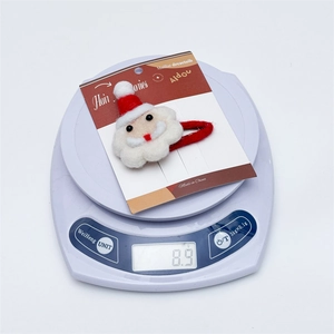 Detailed view of handmade wool felt Santa hair clip on scales weighing 8.9g