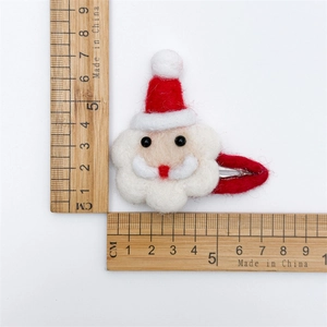 Detailed view of handmade felt Santa Claus hair clip with wooden rulers for size reference