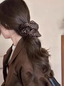 Detail view of a double-layered leopard print velvet hair scrunchie on a ponytail
