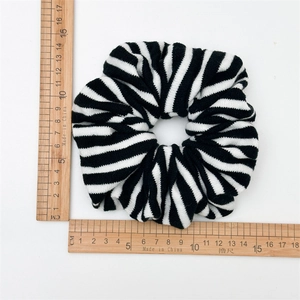 Detail view of a 11cm black and white striped knitted scrunchie on a measuring scale