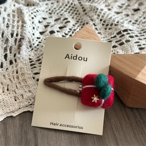 Detail of wool felt Christmas gift box hair clip with green pompom and gold snowflake