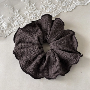Vue détaillée d'un grand chouchou noir à volants avec texture de tissu côtelé et bordure
