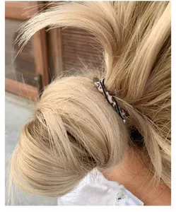 Dettaglio dell'elastico per capelli con stampa leopardata su uno chignon biondo