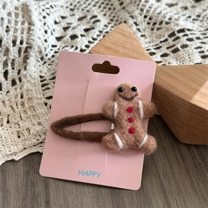 Close-up of wool felt gingerbread man hair clip with intricate white details and a knit base