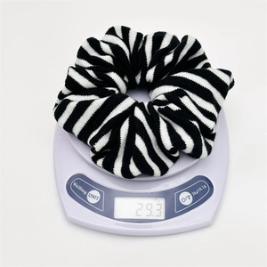 Black and white striped knitted hair scrunchie shown weighing 29.3g on a digital scale