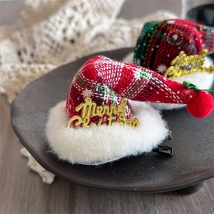 Detail von roten karierten Weihnachts-Mini-Hut-Haarclips mit Pelzrand und goldener Schrift