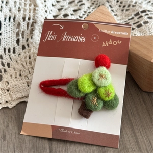 Close-up of handmade wool felt Christmas tree hair clip on branded display card