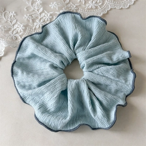 Détail du chouchou plissé bleu clair avec des bords surjetés en gris foncé