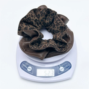 Detail view of stylish leopard velvet scrunchie weighing 52.3g on a digital scale