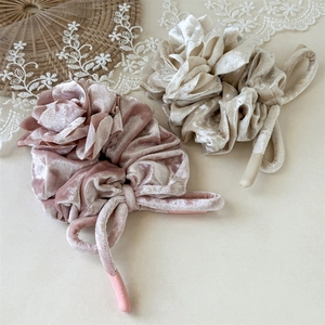 Gros plan de grands chouchous en velours rose et champagne avec de longs rubans pendants