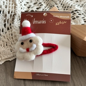 Detail of wool felt Santa Claus hair clip with festive red hat and white beard design