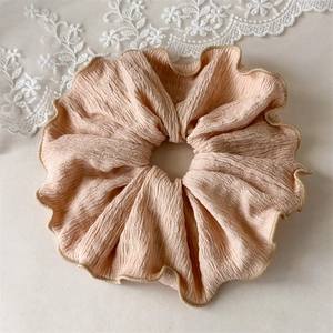 Détail d'un grand chouchou rose poudré avec texture plissée et bordure ondulée