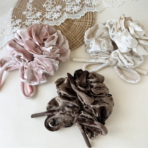 Vue détaillée de trois chouchous en velours avec nœuds en tons rose, beige et chocolat