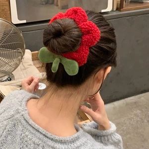 Coletero de flor de lana roja con hojas verdes usado en un peinado de moño alto
