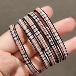 Dettaglio di elastici per capelli ad alta elasticità con motivo a quadri beige nero rosso
