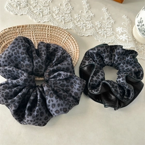 Detail of leopard print velvet hair scrunchies with faux leather stitching textures
