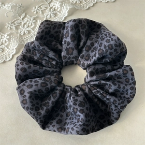 Detailed macro view of gray leopard print velvet fabric texture on a soft scrunchie