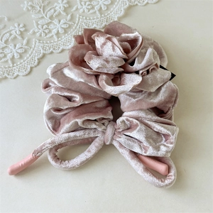 Vue détaillée du chouchou en velours rose poudré avec fleur de rose et rubans longs
