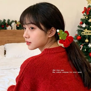 Detail of red velvet Christmas tree scrunchie worn on hair in a cozy festive bedroom setting