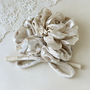 Détail d'un chouchou élégant en velours champagne avec texture plissée et satinée