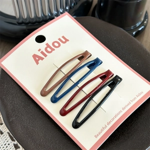 Close-up of four-piece set of teardrop hair clips in dark colors on elegant packaging