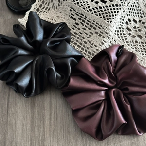Detail of premium oversized silk scrunchies in black and burgundy with smooth satin texture