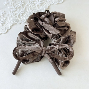 Vue détaillée du chouchou en velours marron foncé avec nceud floral et texture douce