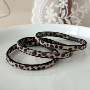 Set di tre elastici per capelli leopardati su un elegante piatto in ceramica bianca