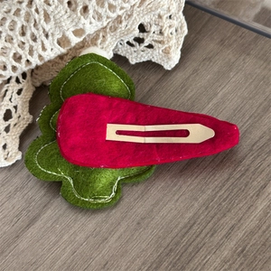 Close-up of handmade felt Christmas hair clip with silver metal BB pin on wood background