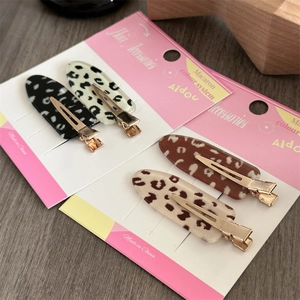 Haarklammern mit Leopardenmuster in vier Farben und goldenen Metallclips auf Karte