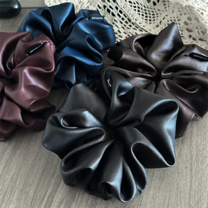 Detail of four handmade satin hair scrunchies in black blue brown and burgundy colors