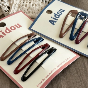 Close-up of four colorful metallic teardrop hair clips on a card with lace background