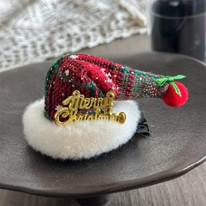 Detail von roter Karo-Weihnachtsmütze-Haarklammer mit Schneemustern und goldener Schrift