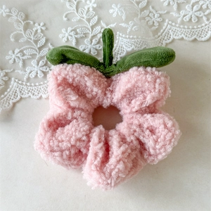 Detalle de coletero de flores de felpa rosa con hojas verdes sobre encaje