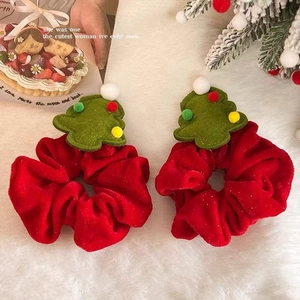 Detail of red velvet Christmas tree scrunchies with gold glitter on a white faux fur rug