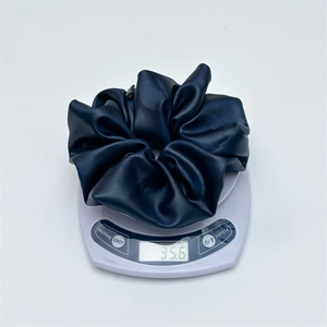 Detail shot of navy blue satin scrunchie on scale showing weight of 35.6 grams