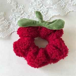 Primer plano de un coletero de fresa de peluche en forro polar rojo con detalle de hoja verde