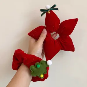 Detail of red velvet Christmas scrunchies with green tree, bow, and small gold bell