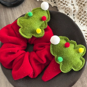 Close-up of red velvet scrunchie and hair clip with felt Christmas tree decoration