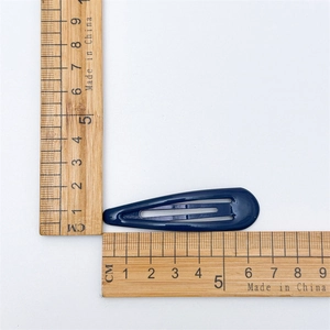 Close-up of a 5cm dark blue teardrop BB hair clip with dimensions on wooden rulers