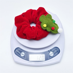 Detail showing red velvet Christmas tree scrunchie weighing 12.0g on a digital scale