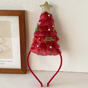 Dettaglio di un cerchietto con albero di Natale rosso decorato con stelle dorate e glitter