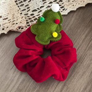 Detail of red velvet Christmas scrunchie with green felt tree on wooden background
