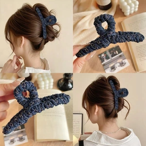 Détail de la pince à cheveux en denim tissé avec chaîne dorée pour chignons élégants