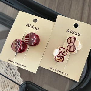 Detail view of red and cream acrylic hair clips with Lucky Girl text on a display card