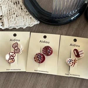 Three-piece set of red acrylic hair clips with retro patterns on display card